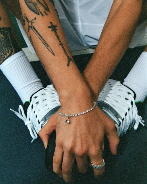 Close-up of a light-skinned adult male's hands wearing a diamond tennis bracelet and ring, holding a black bowling ball.
