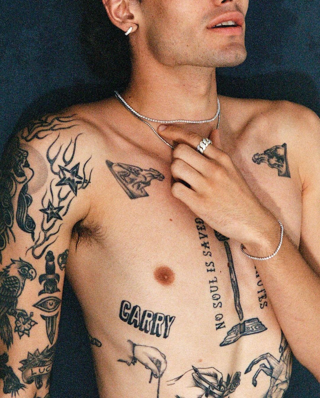 Close-up portrait of a tattooed man wearing diamond tennis chains and a ring, photographed by Cully Wright.