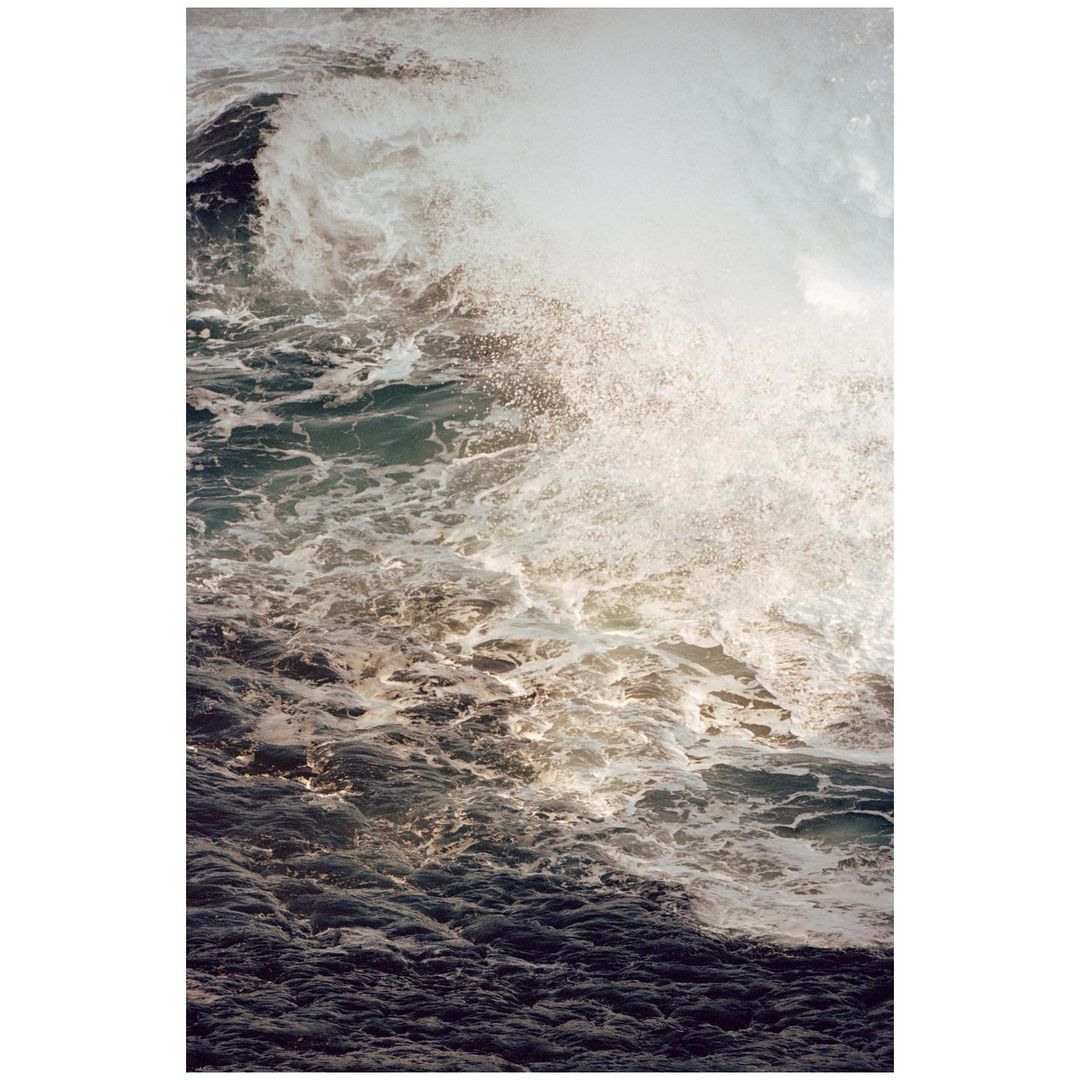 Powerful ocean wave with white foam and dark blue water. Seascape of a dynamic wave crashing with a vertical orientation.