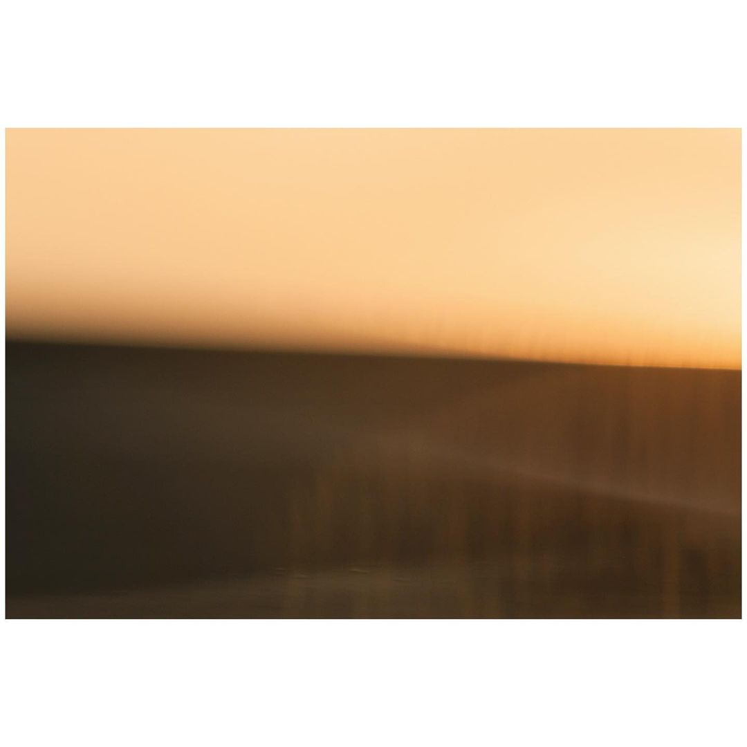 Blurred landscape of warm golden light meeting the horizon, creating a serene, abstract image with a sense of depth and tranquility.
