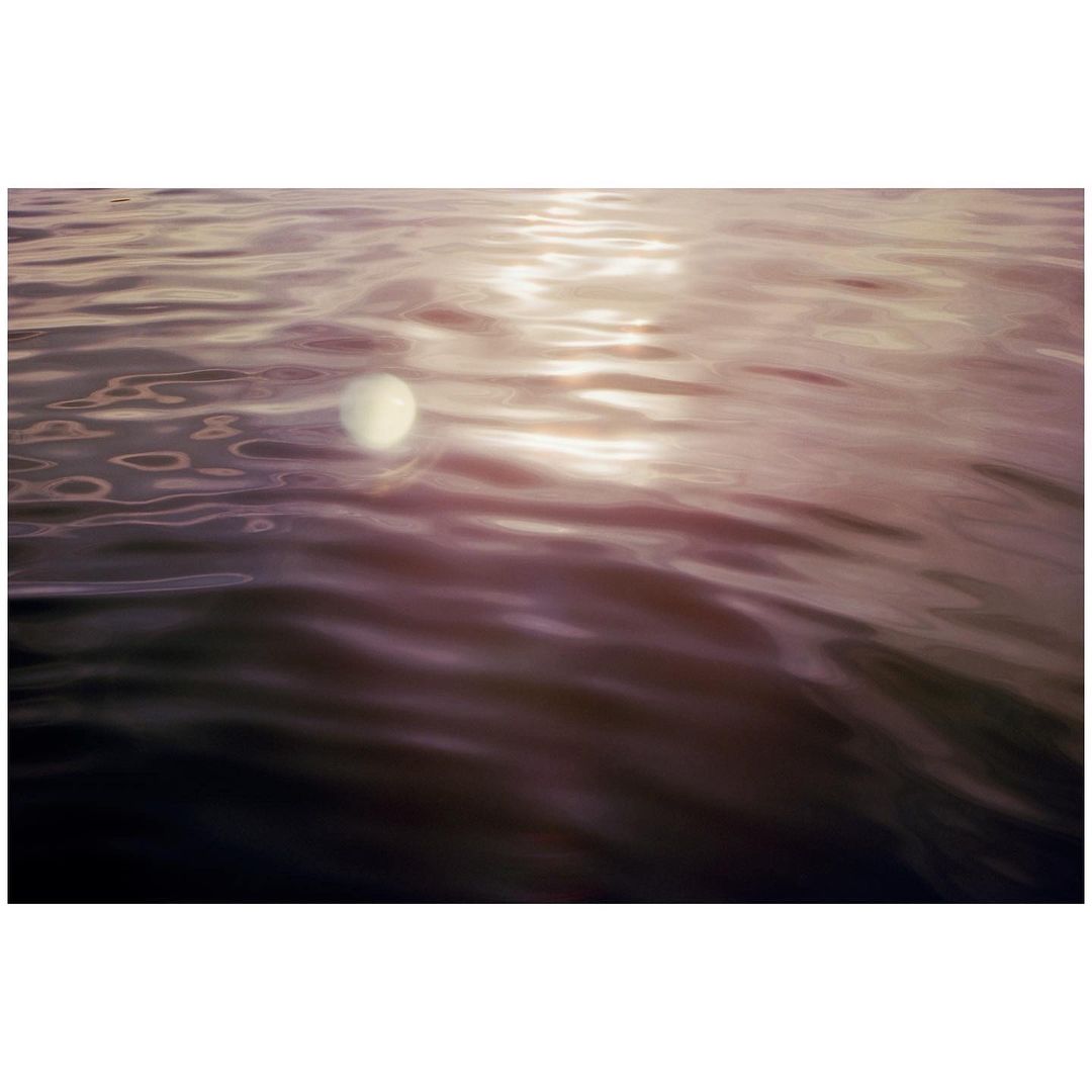 An atmospheric view of water with gentle waves, reflecting the sunlight and sky, creating a tranquil and ethereal landscape.