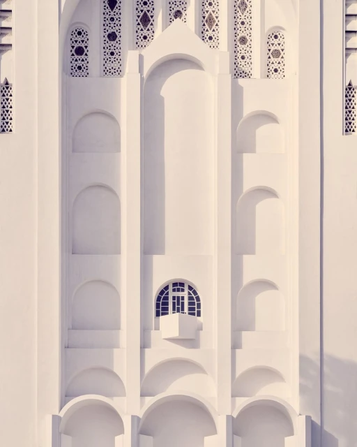 Architectural detail of an ornate white building facade with arched openings and a small window, showcasing intricate design and symmetry.