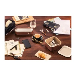 Overhead flat lay of an organised dark wooden desk featuring a coffee cup, smartphone, watch, papers, and small leather storage boxes.