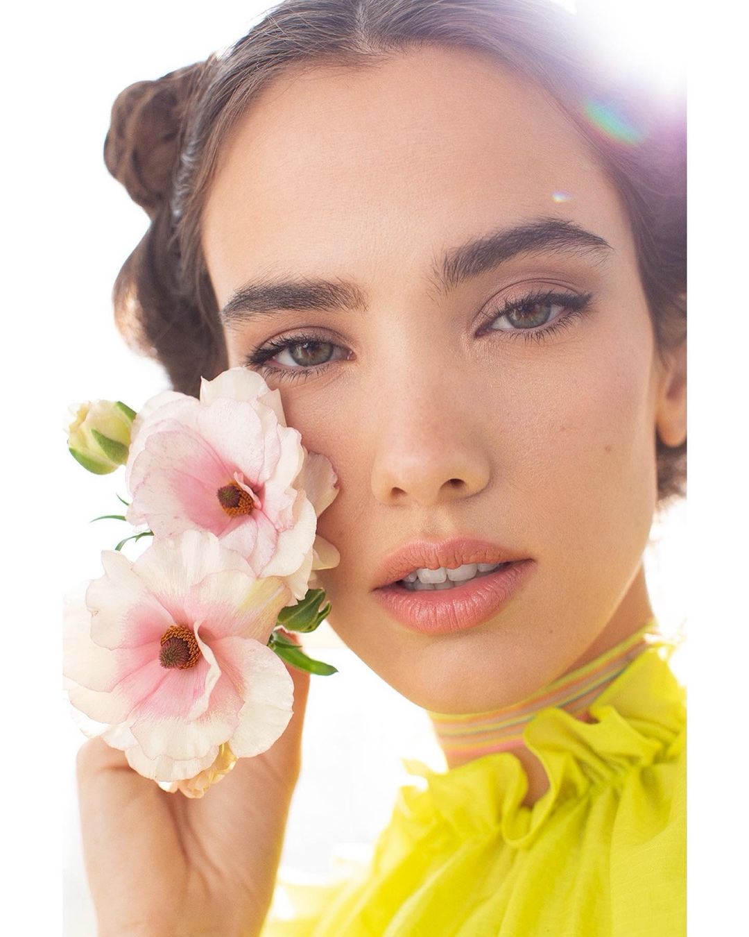 Close-up portrait of a woman with pink flowers, featuring soft lighting, fair skin, and a delicate, pastel-colored aesthetic. Beauty shot.