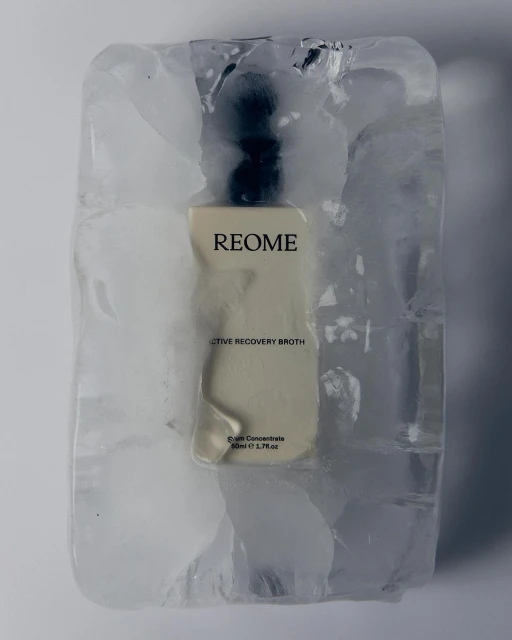 Close-up of Reome skincare serum bottle frozen in a block of ice against a white background, showcasing product preservation and innovation.
