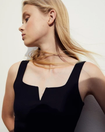 Close-up of a young woman with blonde hair wearing a black top in a studio setting, showcasing beauty and fashion.