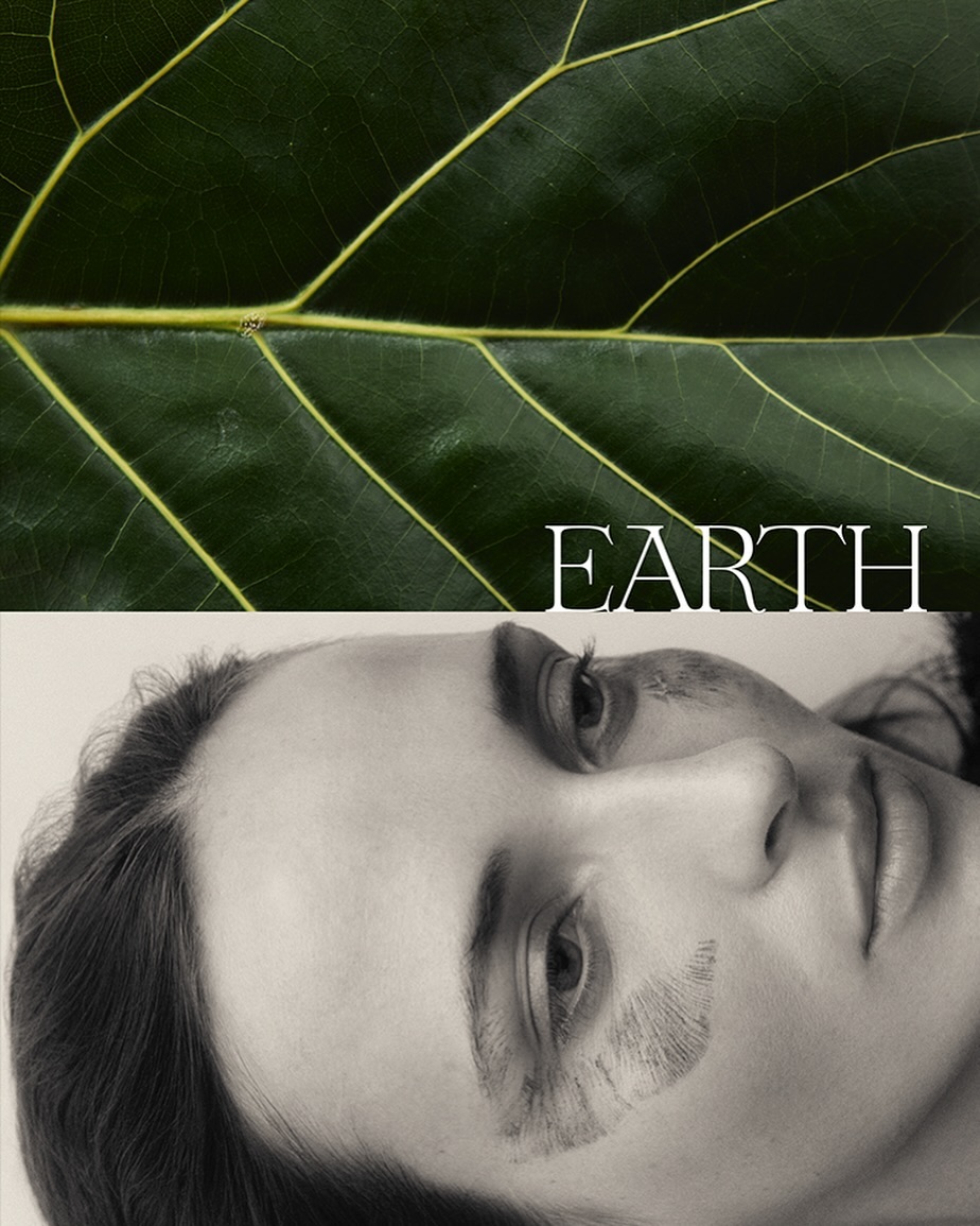 Close-up portrait of a woman with earthy markings on her face beneath a large green leaf with visible veins.
