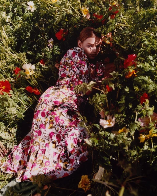 A woman in a floral dress lying in a field of wildflowers, creating a vibrant and natural portrait with a focus on nature and beauty.