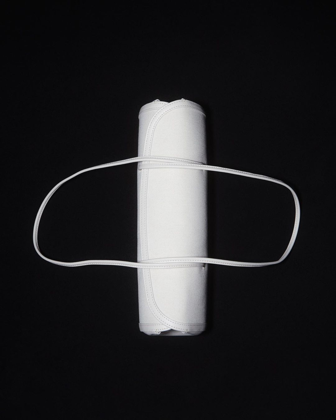 Rolled white textile with a white elastic band on a black background, studio lit for a clean, minimal product shot.