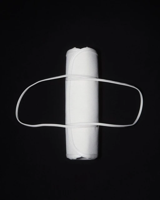 Rolled white textile with a white elastic band on a black background, studio lit for a clean, minimal product shot.