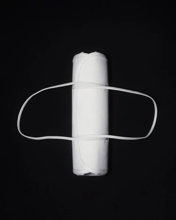 Rolled white textile with a white elastic band on a black background, studio lit for a clean, minimal product shot.
