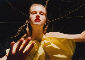 Close-up portrait of a woman wearing a yellow top with red lipstick under direct flash lighting at night