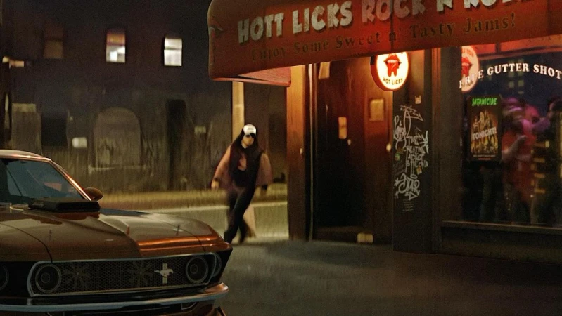 Classic Mustang parked outside Hott Licks Rock n Roll, with a person walking toward the entrance in a nighttime urban setting.
