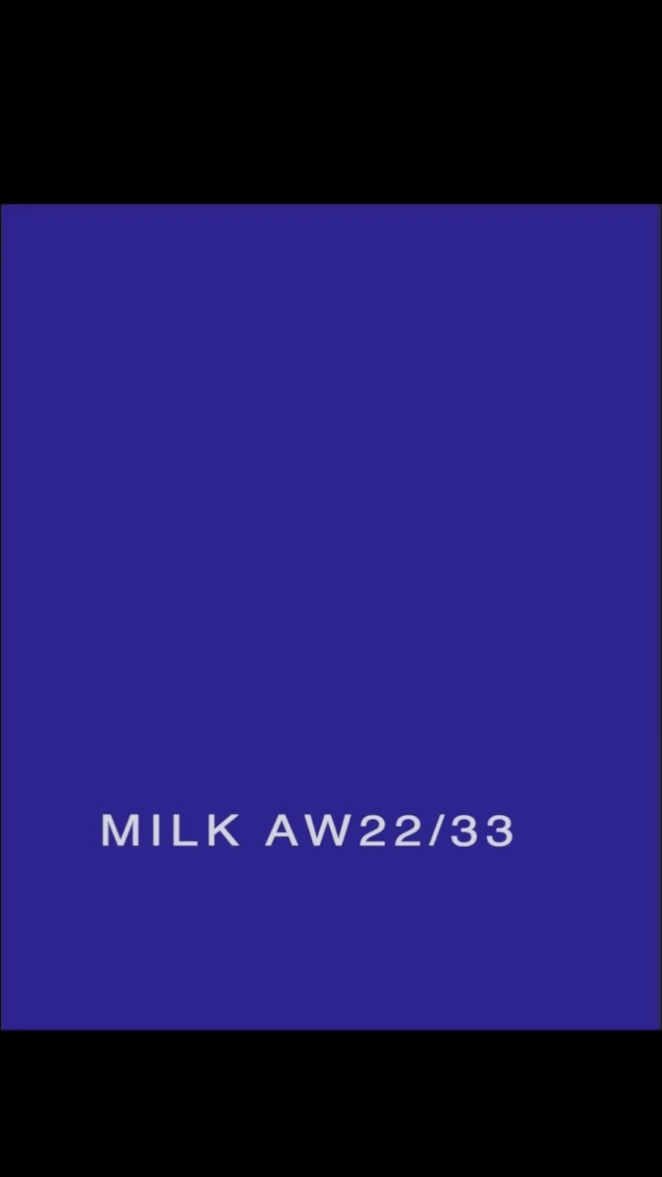 Solid purple-blue backdrop with the text MILK AW22/33 displayed, creating a simple and modern visual statement.