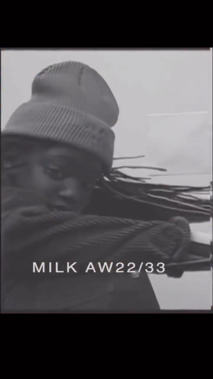Monochrome studio shot of a Black adult female model wearing a knit beanie and a corduroy jacket looking at the camera.