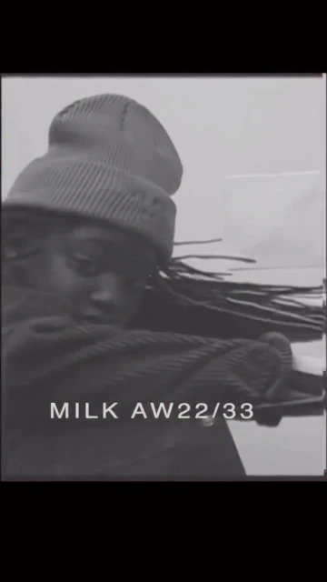 Monochrome studio shot of a Black adult female model wearing a knit beanie and a corduroy jacket looking at the camera. 