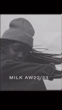 Monochrome studio shot of a Black adult female model wearing a knit beanie and a corduroy jacket looking at the camera. 