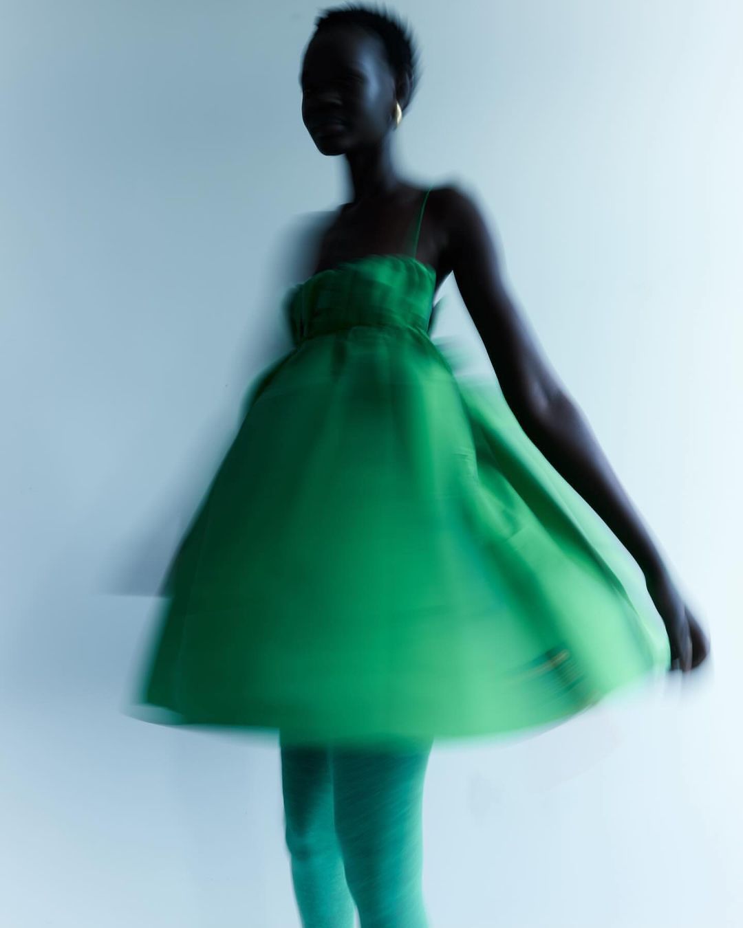 Woman in green dress with motion blur against white background in studio fashion shot for Visie creative directory.