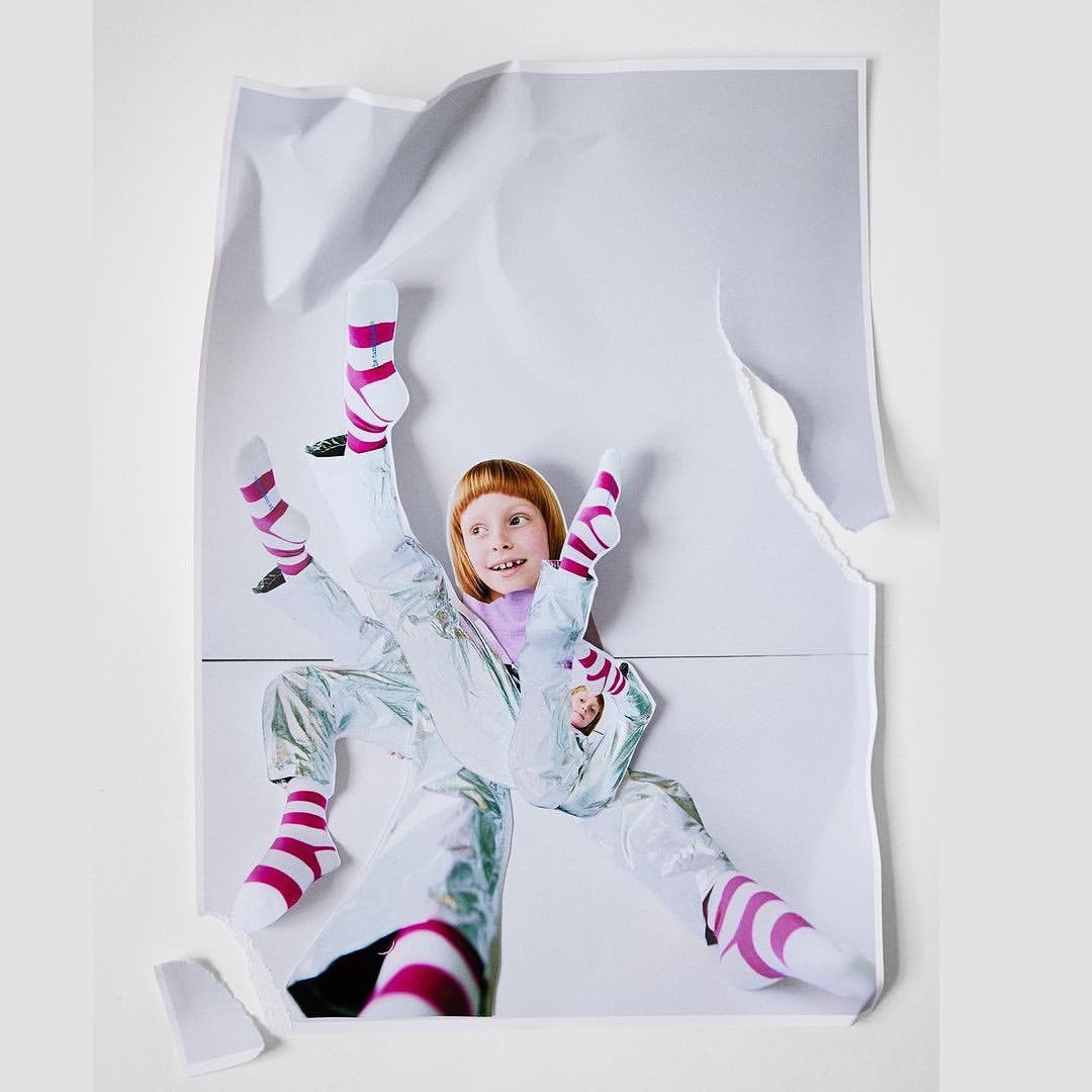Collage of a girl in a silvery jumpsuit and striped socks on a torn white paper background, playful and creative imagery.