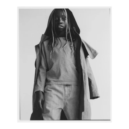 Child wearing striped long-sleeve shirt and hooded jacket against plain studio background by Damian Weilers.