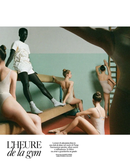 Group of young women in leotards and athletic wear pose in a gymnasium with balance beams and green and white walls in a bright editorial style.