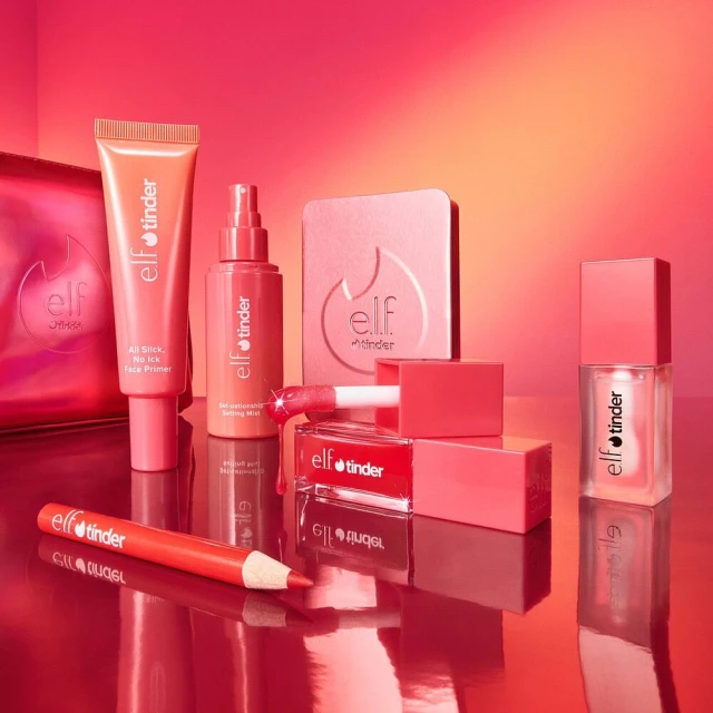 Still life studio shot of e.l.f. Cosmetics 'tinder' product line, including primer, setting spray, powder, lip gloss, lip stick, and liner.