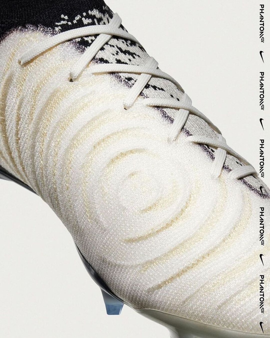 Close-up studio shot of a white Nike Phantom GX soccer cleat with laces and black detailing against a white backdrop.