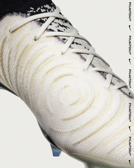 Close-up studio shot of a white Nike Phantom GX soccer cleat with laces and black detailing against a white backdrop. 