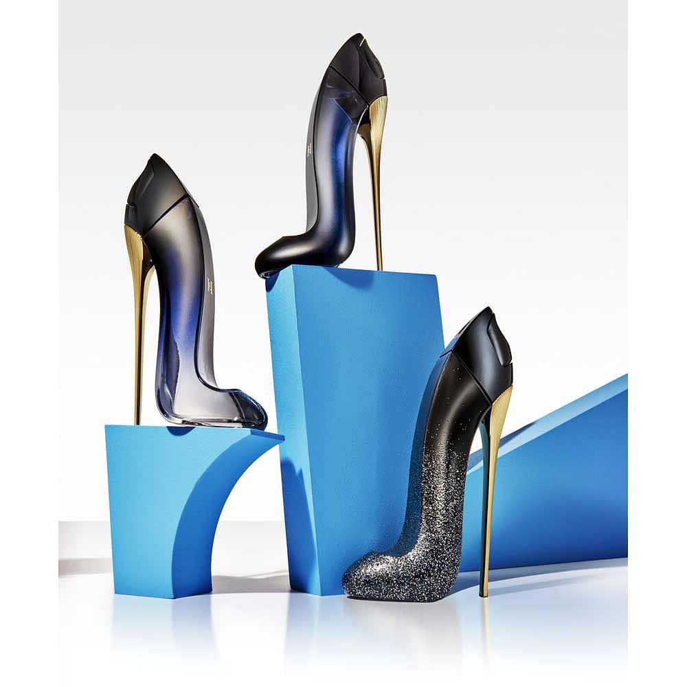 Three perfume bottles shaped like stiletto heels on blue blocks against a white backdrop, showcasing a modern beauty product display.