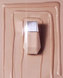 Fenty Beauty foundation bottle positioned centrally over smooth liquid makeup swatches by photographer Dan Forbes.
