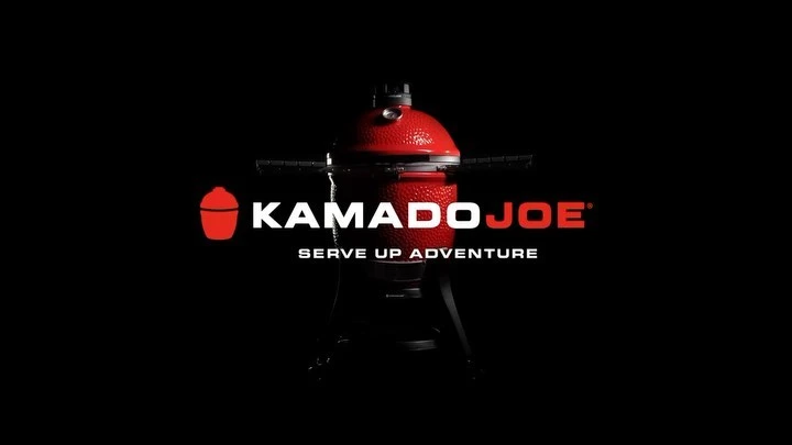 Red Kamado Joe ceramic grill on a black background, featuring the brand logo and tagline Serve Up Adventure.