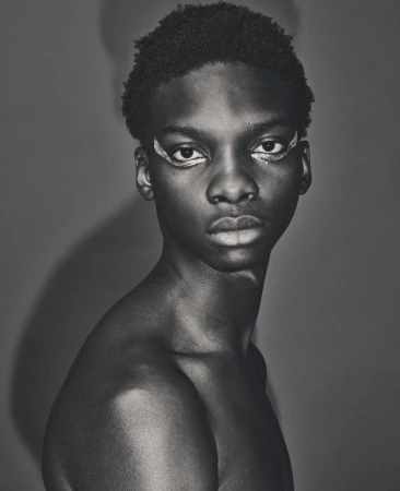 Close-up black and white portrait of a young Black man with painted eyeliner by Dan Jackson