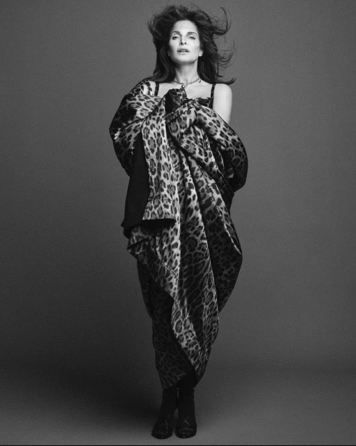 Monochrome full-length portrait of a woman with shoulder-length hair, draped in a patterned shawl, posing in front of a grey backdrop.
