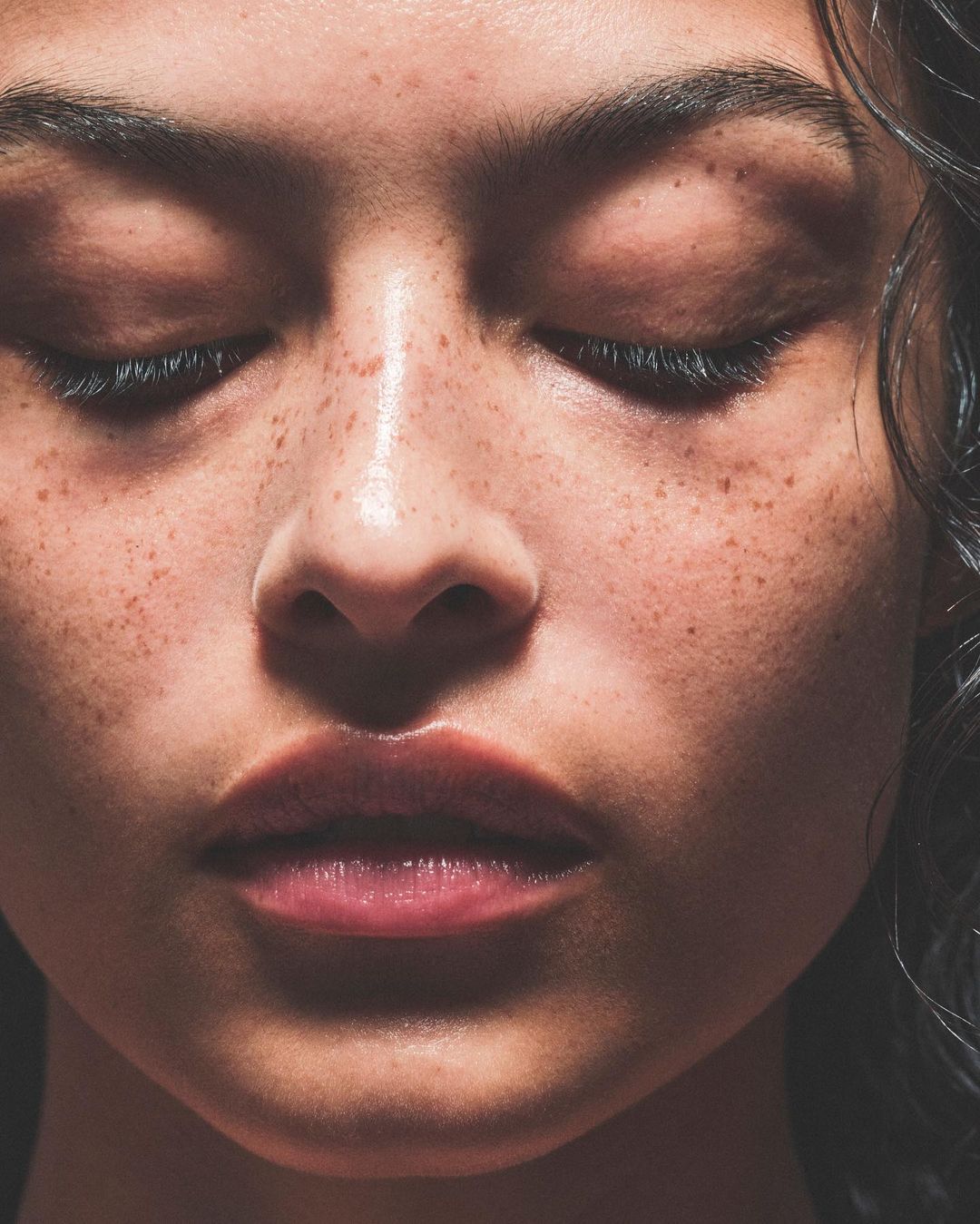 Close-up portrait of a woman with freckles and closed eyes photographed by Dan Jackson.