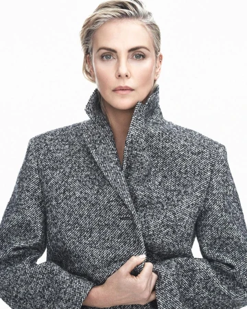 Portrait of adult female with short blonde hair wearing a gray tweed jacket against a bright white background in a photo studio.