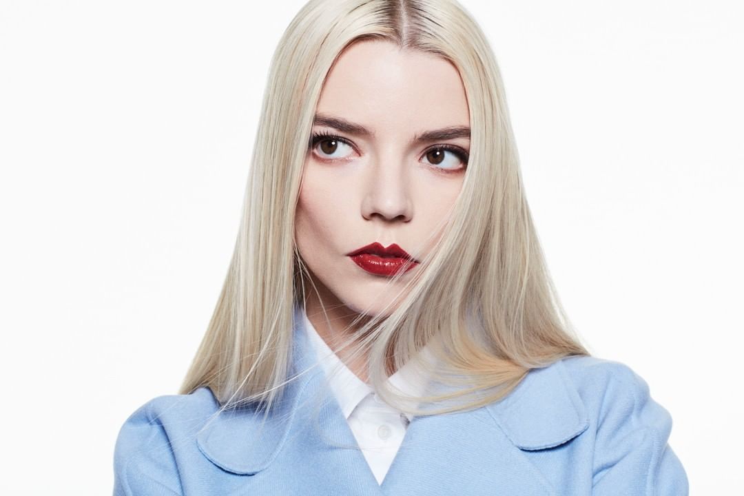 Anya Taylor-Joy portrait: Young adult female with blonde hair, wearing a light blue jacket in a studio setting with bright lighting.