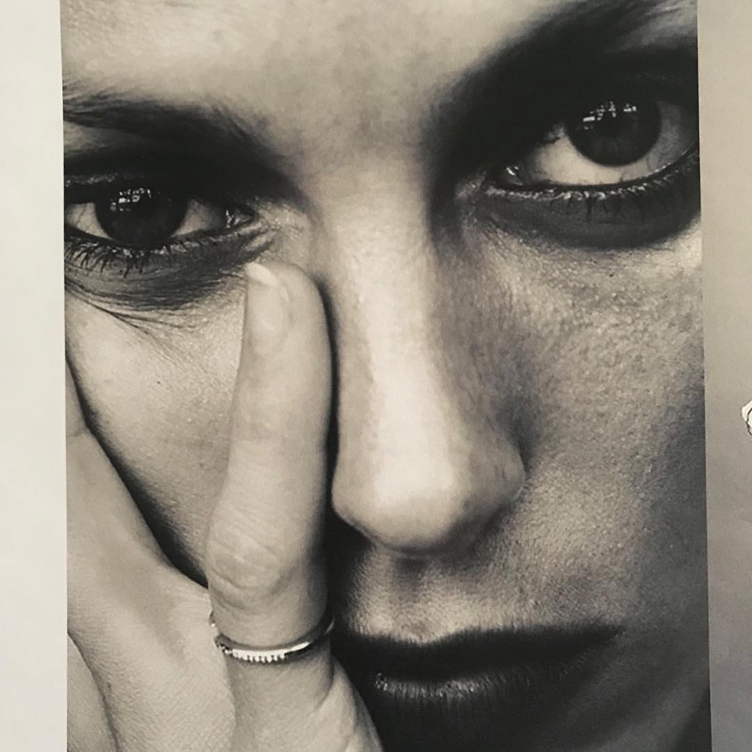 Close-up black-and-white portrait of an adult woman with a ring, her hand partially covers her face, emphasizing her eyes.