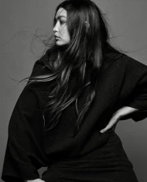 Monochrome portrait of a woman with long flowing dark hair wearing a black garment against a grey background photographed by Dan Jackson