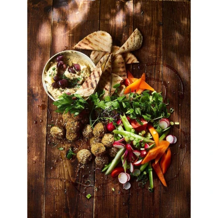 Overhead shot of falafel, hummus, pita bread, and vegetables on a wooden surface, creating a vibrant and appetizing food display.