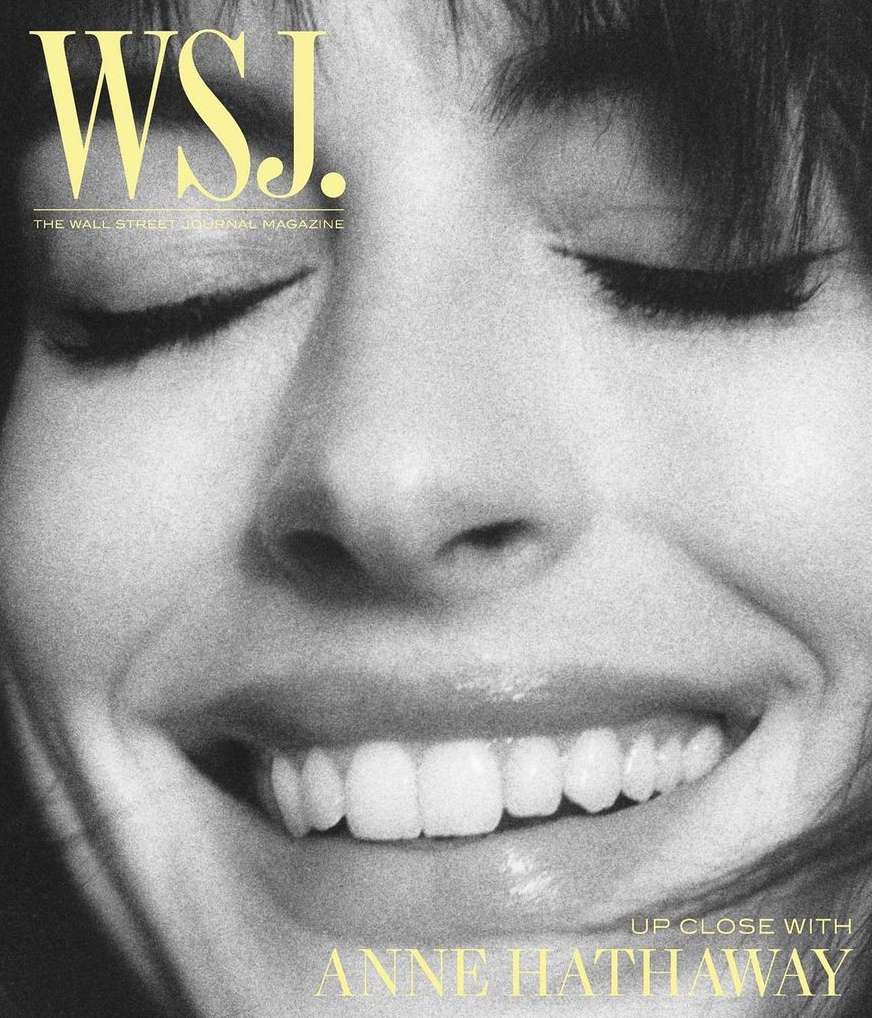 Close-up portrait of Anne Hathaway on WSJ. magazine cover with a soft-focus black and white filter. The focus is on her closed-eye smiling face.