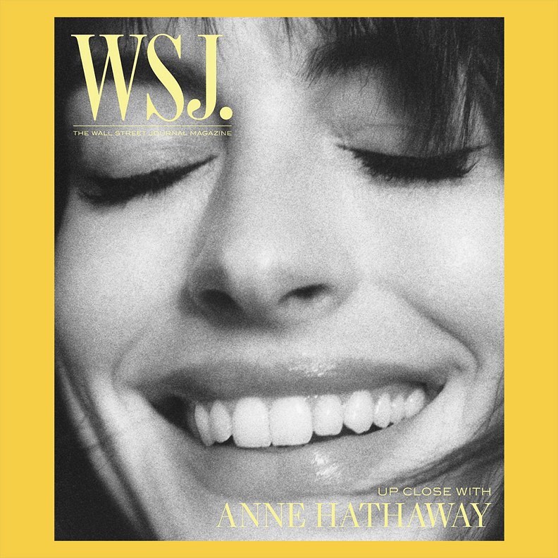 Close-up of Anne Hathaway smiling on the cover of WSJ. Magazine with a yellow border. Focus on facial features with a shallow depth of field.