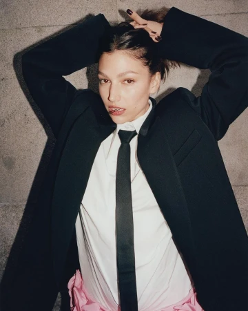 Woman in an oversized black blazer, white shirt, and black tie holding her hair up, photographed by Dan Martensen.