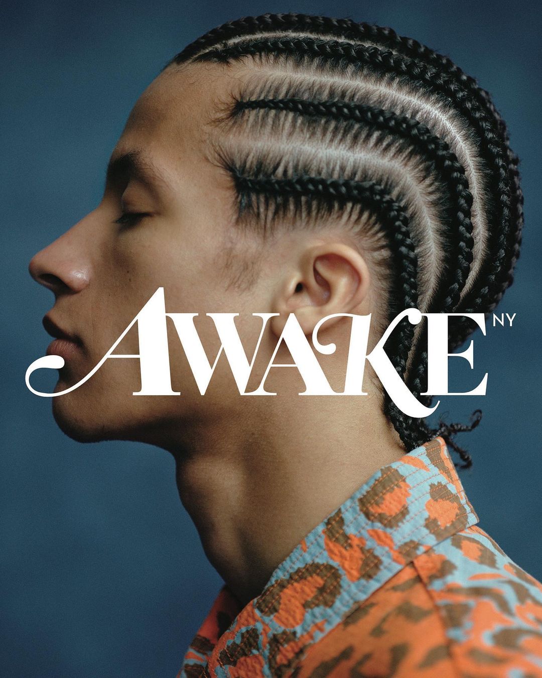 Profile portrait of a young adult male with braided hair wearing a patterned shirt against a blue background with text overlay.
