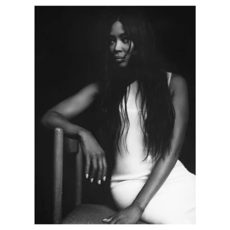 Monochrome portrait of Naomi Campbell seated on a chair wearing a light-coloured dress, captured by Dan Martensen.