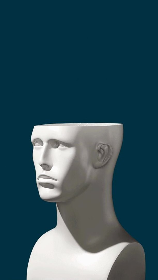 A white plaster head sculpture stands against a teal background with dramatic lighting emphasizing its smooth texture and blank expression.