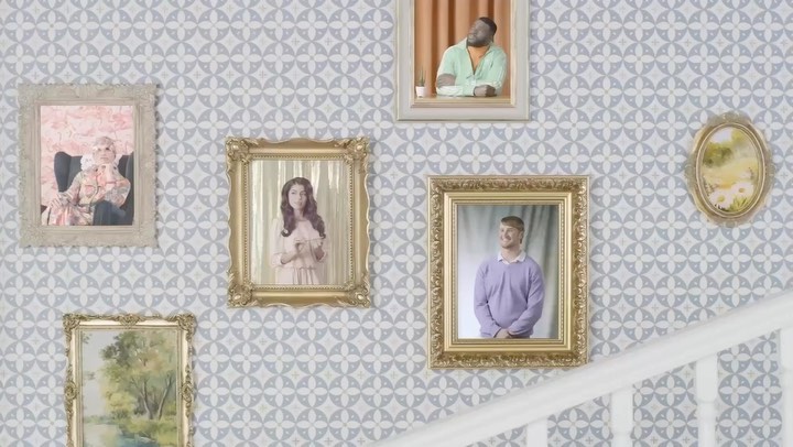 Group of portraits in ornate frames hanging on patterned wall with staircase, showcasing diverse individuals in formal settings and attire.