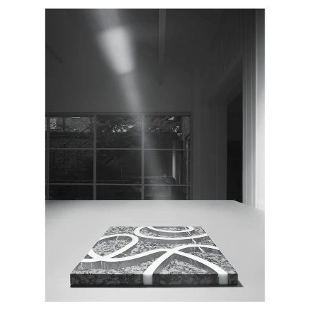 A patterned marble slab with white lines rests on a white table indoors, illuminated by a beam of light coming through a window.