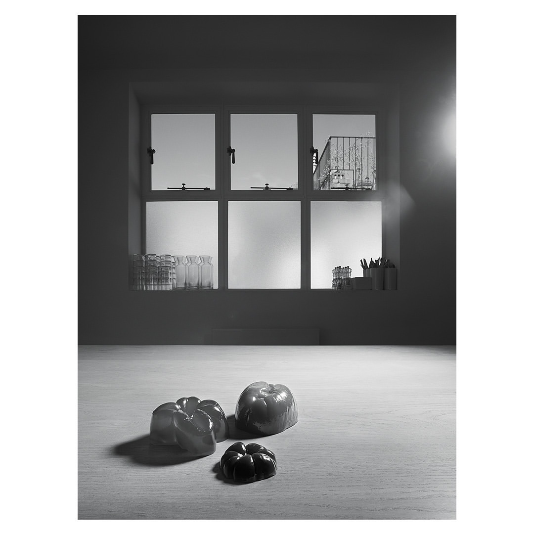 Black and white still life with bell peppers on a table in front of a window providing daylight in an indoor setting.