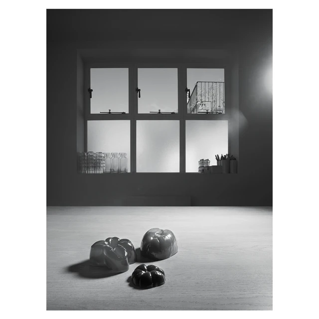Black and white still life with bell peppers on a table in front of a window providing daylight in an indoor setting.