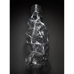 Crushed transparent plastic bottle photographed centrally against a dark grey seamless background